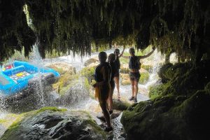 Rafting group taking a refreshing break in a cave beneath a cascading waterfall along the Cetina River. Group resting inside a cave under a waterfall during rafting on the Cetina River