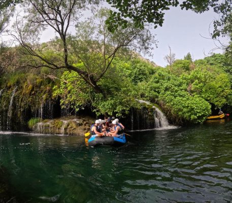Rafting grupa uživa u osvježavajućem odmoru ispod slapova na rijeci Cetini. Grupa odmara ispod slapova tijekom raftinga na rijeci Cetini