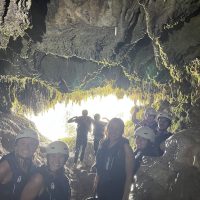 Children and parents smile while discovering the cave, enjoying a unique experience. Family exploring a cave as part of the rafting adventure