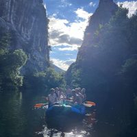 Participants float calmly through a peaceful section of the river, surrounded by cliffs and forest. Tourists rafting in the untouched nature of the Cetina River