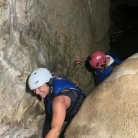 Djeca i roditelji s osmijehom istražuju špilju, uživajući u posebnom iskustvu. Friends exploring cave and climbing in Dalmatia