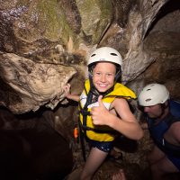 Kid on a tour exploring cave in rafting gear