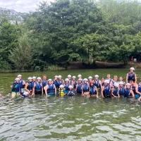 Roditelji i djeca zajedno veslaju i uživaju u sigurnoj rafting avanturi. Large party in a Cetina river posing and swimming in a Cetina