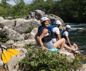 Visitors enjoying a peaceful rest on the riverbank of the Cetina River, soaking in the natural beauty of the area. People relaxing on the shore of the Cetina River surrounded by nature