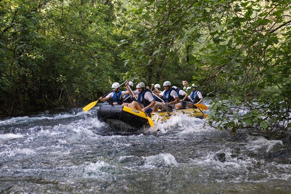 Adventurous rafting group bravely navigating powerful waterfalls during their thrilling ride on the Cetina River near Omiš. Group of rafters battling strong waterfalls on the Cetina River