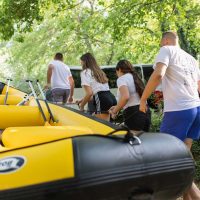 Teamwork in action as a group carries their raft to the Cetina River, ready for an exciting rafting adventure. Group carrying a raft towards the Cetina River for an adventure