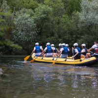udionici veslaju u punoj snazi dok ih voda nosi kroz pjenušave valove Grupa na raftingu u Splitu